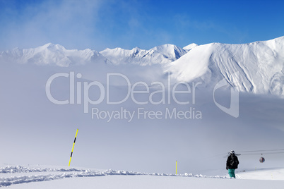 Snowboarder on off-piste slope and mountains in mist