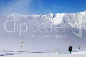 Snowboarder on off-piste slope and mountains in mist