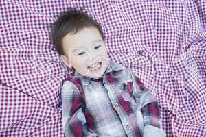 Cute Young Mixed Race Boy Laughing On Picnic Blanket
