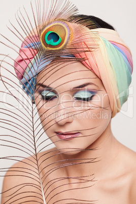 Portrait of young beautiful woman in a turban and peacock feathe
