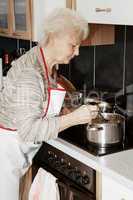 Elderly woman in cooking in the kitchen