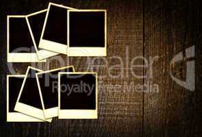 Old weathered blank instant photos on dark wooden table