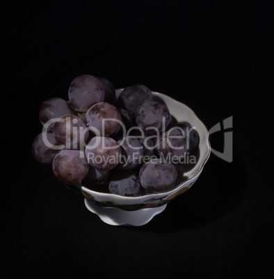 vase with grapes on a black background