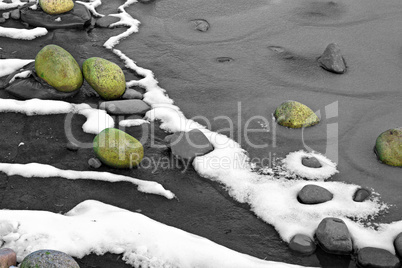 Moss covered rocks on frozen lake