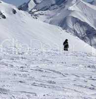 Ski trail and snowboarder in sun winter day