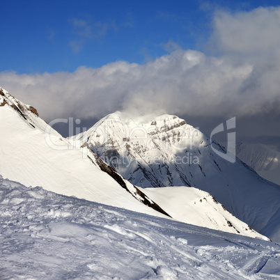 Off-piste slope and sunlit mountains at evening