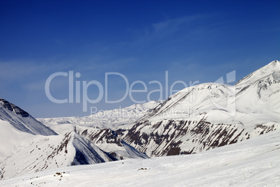 Ski slope and snowy mountains in sun day