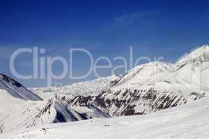 Ski slope and snowy mountains in sun day