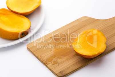 Third Of A Mango And Its Juice On Wooden Board
