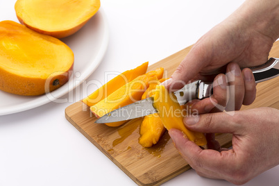 Close-up Of Two Hands Peeling Juicy Mango Pieces