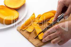 Two Hands Dicing A Mango Wedge With A First Cut