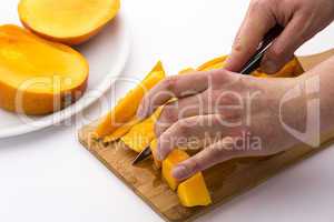 Mango Wedges Being Diced On A Wooden Cutting Board