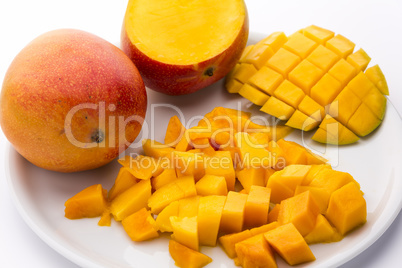 Heap Of Juicy Mango Cubes And Whole Fruit On Plate