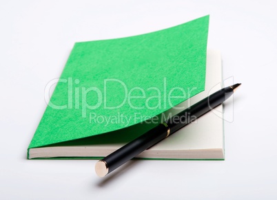 Green notebook and ballpoint pen