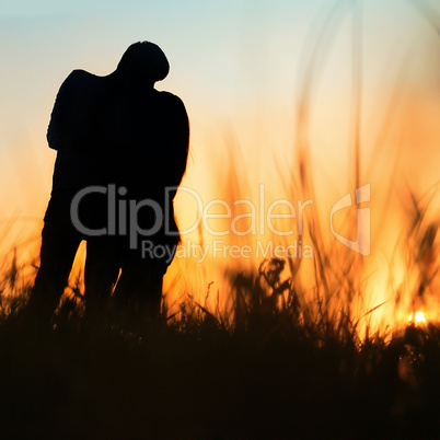 silhouette of a young couple kissing at sunset