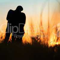 silhouette of a young couple kissing at sunset