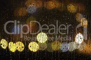 Fensterscheibe mit Regentropfen bei Nacht