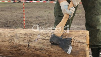 Soldier in camouflage with an ax sharpening log