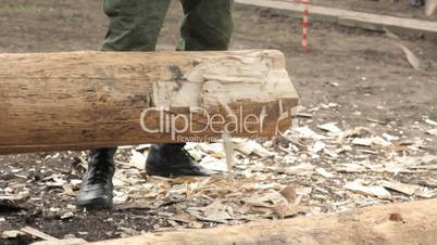 Soldier in camouflage with an ax sharpening log