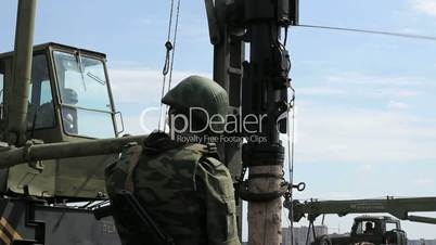 Soldier with ak-47 and working pile driver