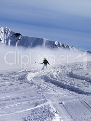 Snowboarder downhill on off-piste slope in sunny day