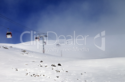 Gondola lifts and ski slope in mist