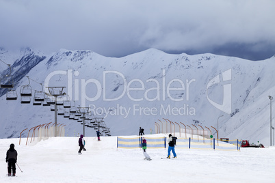 Ski slope with skiers and snowboarders in evening