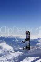 Snowboard in snow on off-piste slope at sun day