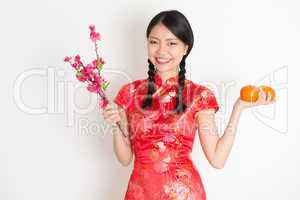 Asian chinese girl holding tangerine orange and plum blossom