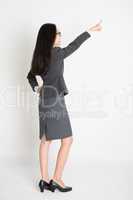 Full body backside Asian business woman pointing
