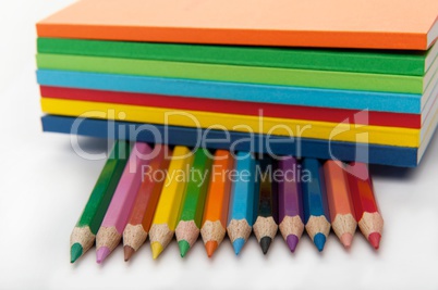 Seven notepads on top of twelve colored pencils