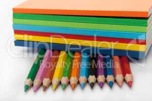Seven notepads on top of twelve colored pencils