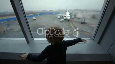 Little boy looking out the window at airport