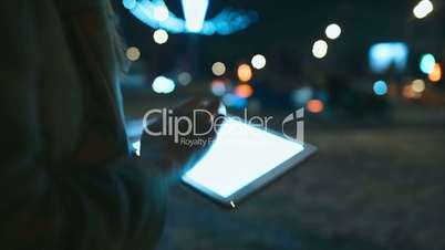 Woman using touch pad while walking in city at night