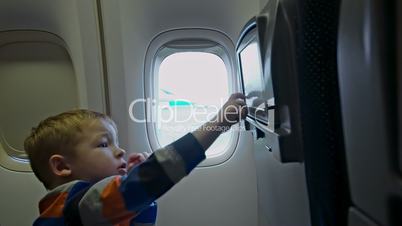 Little boy touching seat monitor in plane