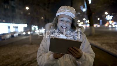 Happy woman walking in the evening street with pad