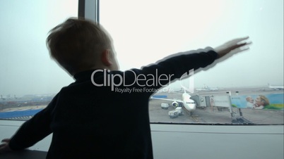 Little boy showing plane with hands looking at it out the window