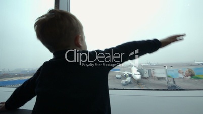 Boy looking at the plane from window and imitating it