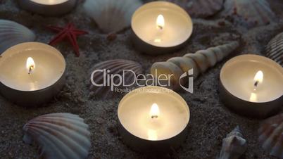 Six candles and some seashells on the sand