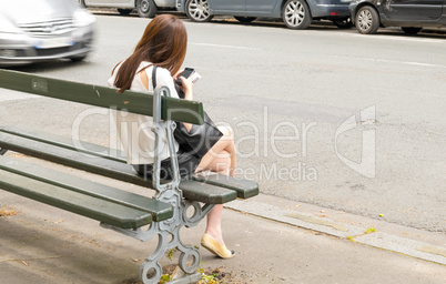 Woman using his mobile phone sitting on a city bench