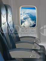 Seating and window inside an aircraft with view of blue sky and clouds
