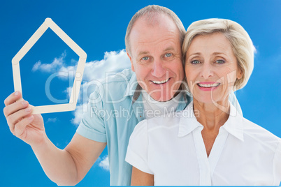 Composite image of happy older couple holding house shape