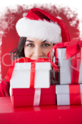 Composite image of festive brunette holding stack of gifts