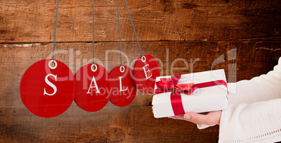 Composite image of woman offering a gift box