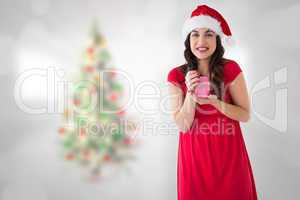 Composite image of brunette in santa hat holding gift