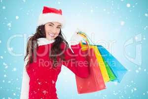 Composite image of festive brunette in winter wear holding shopp