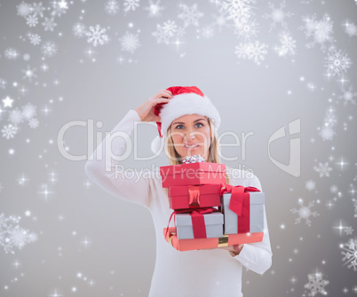 Composite image of confused blonde in santa hat holding gifts