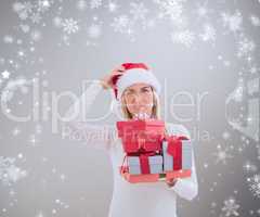 Composite image of confused blonde in santa hat holding gifts