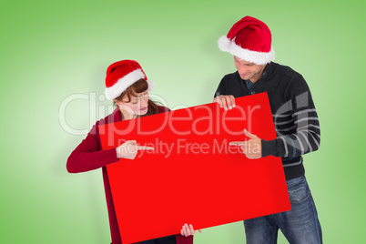Composite image of couple holding a sign
