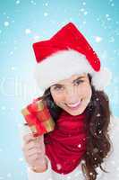 Composite image of happy brunette holding christmas gift